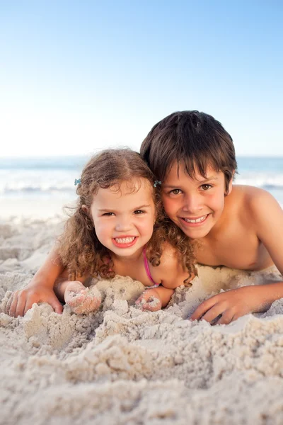 Mały chłopiec i jego siostra, leżenie na plaży — Zdjęcie stockowe
