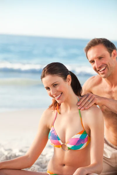 Glücklicher Mann, der Sonnencreme auf den Rücken seiner Freundin aufträgt — Stockfoto