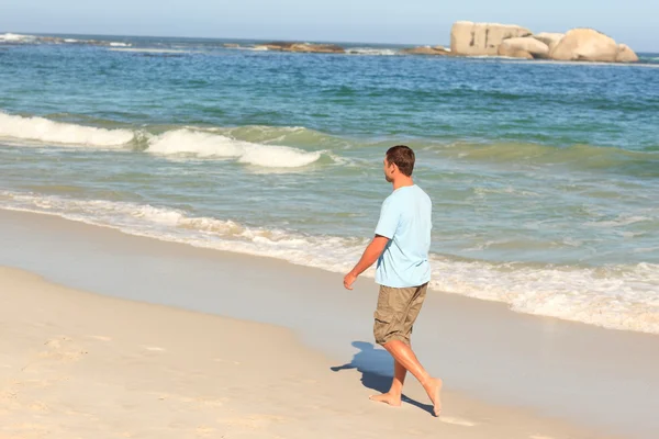 Knappe man wandelen op het strand — Stockfoto