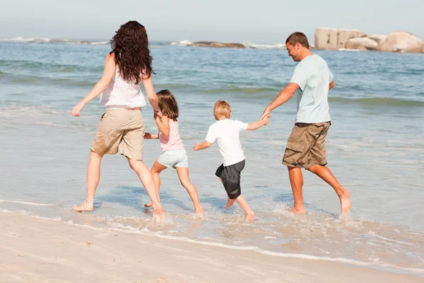 Familjen springer på stranden — Stockfoto