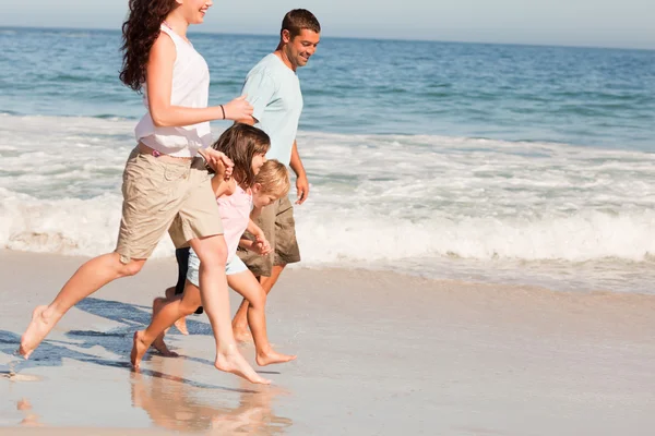 Aile sahilde koşuyor. — Stok fotoğraf