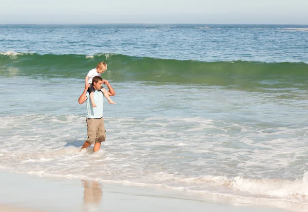 ビーチで息子のおんぶを与える父 — ストック写真