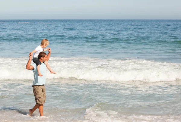 Fadern gav sonen en piggyback på stranden — Stockfoto