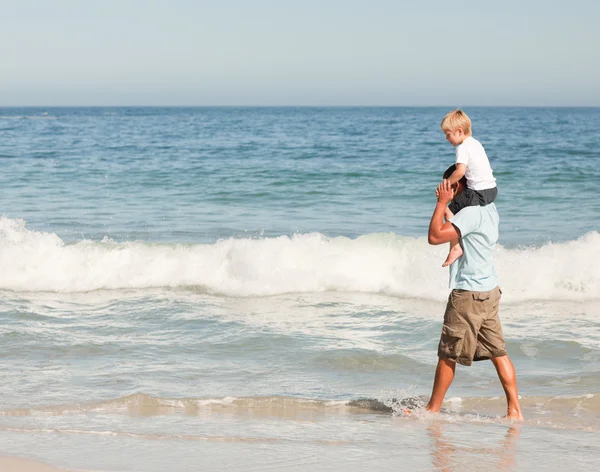 Père donnant un fils un piggyback sur la plage — Photo