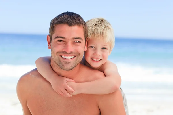 Lächelnder Vater mit Sohn huckepack am Strand — Stockfoto