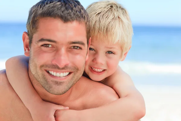 Sorrindo pai ter filho um piggyback na praia — Fotografia de Stock