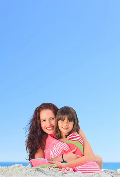 Mulher sorridente com sua filha em uma toalha — Fotografia de Stock