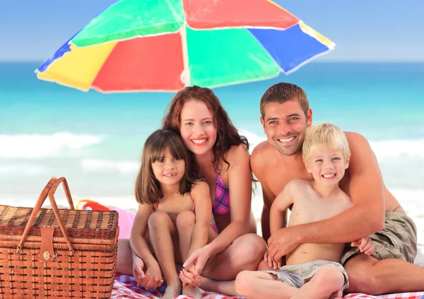 Sahilde bir sol şemsiyesi altında piknik aile — Stok fotoğraf