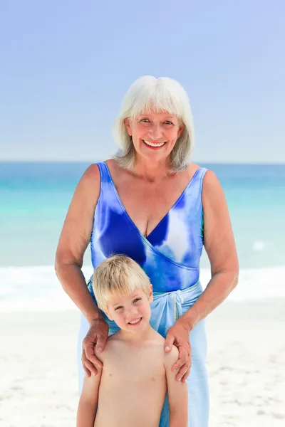 Mormor med sitt barnbarn på stranden — Stockfoto