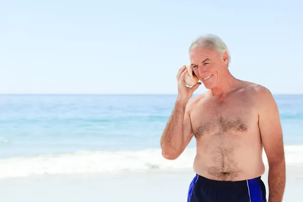 Starší muž poslouchá jeho shellu — Stock fotografie