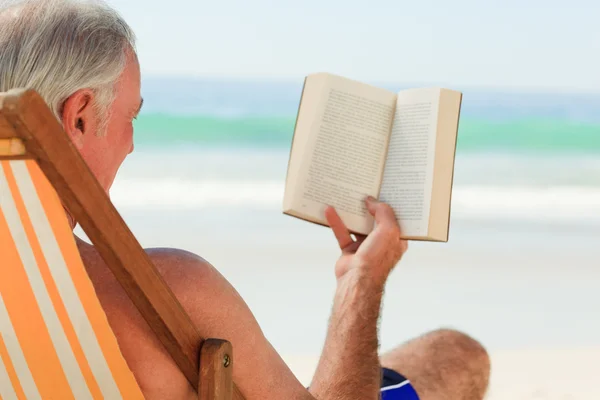 Älterer Mann liest am Strand ein Buch — Stockfoto