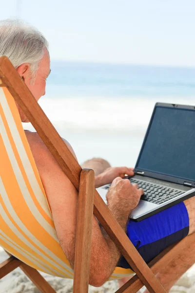 Kumsalda yaptığı dizüstü bilgisayarda çalışan adam — Stok fotoğraf