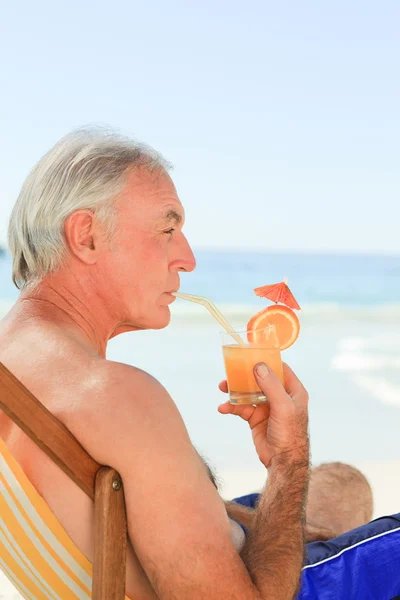 Emekli adam sahilde kokteyl içme — Stok fotoğraf