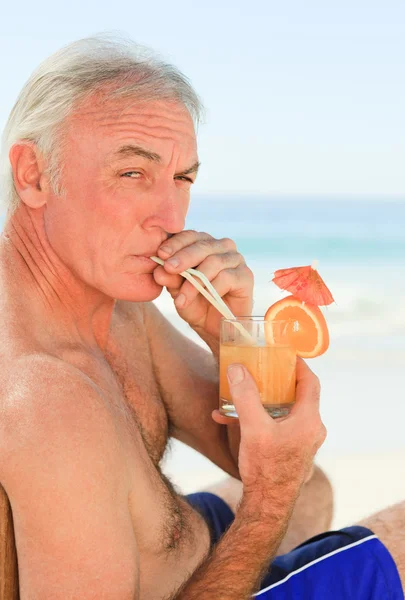 Відставний чоловік п'є коктейль на пляжі — стокове фото