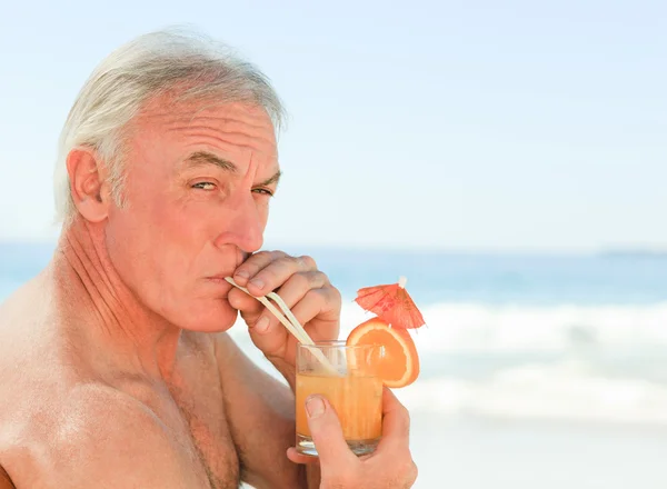 Hombre retirado bebiendo un cóctel en la playa — Foto de Stock