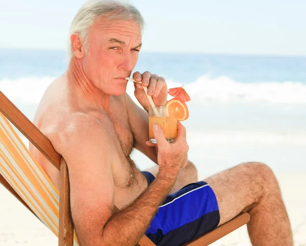 Gepensioneerde man drinken een cocktail op het strand — Stockfoto