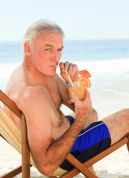 Uomo in pensione che beve un cocktail in spiaggia — Foto Stock