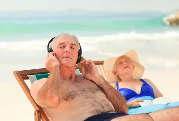 Człowiek, słuchanie muzyki, podczas gdy jego żona śpi — Zdjęcie stockowe