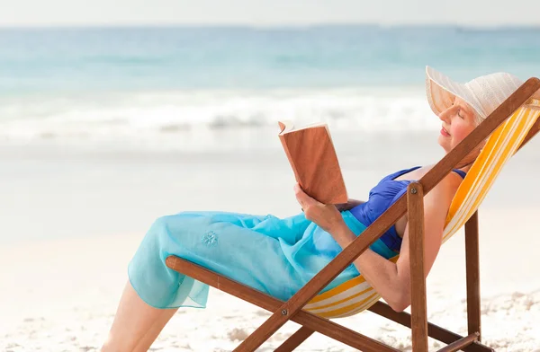Yaşlı kadın sahilde bir kitap okuma — Stok fotoğraf