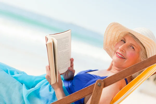 Ηλικιωμένη γυναίκα διαβάζοντας ένα βιβλίο στην παραλία — Φωτογραφία Αρχείου