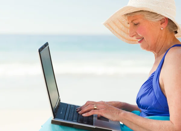 Glad kvinna som arbetar på sin laptop på stranden — Stockfoto