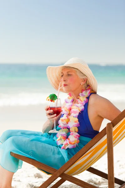 Mulher tomando um coquetel em sua cadeira de praia — Fotografia de Stock