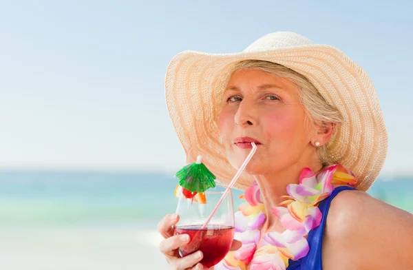 Mulher tomando um coquetel em sua cadeira de praia — Fotografia de Stock