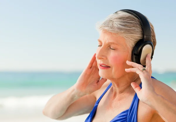 年配の女性のビーチで音楽を聴く — ストック写真
