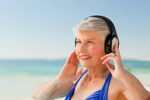 Senior mulher ouvindo música na praia — Fotografia de Stock