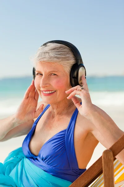 Emeryturze kobieta słuchanie muzyki na plaży — Zdjęcie stockowe