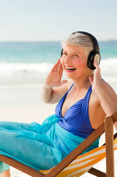 Συνταξιούχος γυναίκα ακούγοντας μουσική στην παραλία — Φωτογραφία Αρχείου