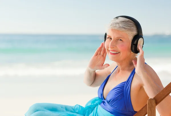 退職女性はビーチで音楽を聴く — ストック写真