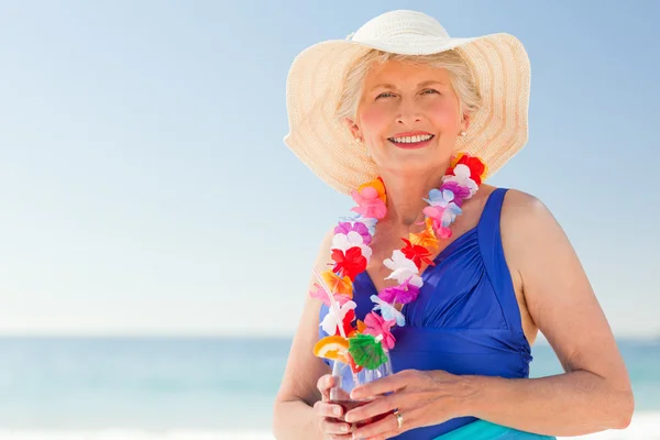 Ηλικιωμένη γυναίκα πίνοντας ένα κοκτέιλ στην παραλία — Φωτογραφία Αρχείου