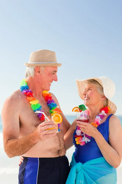 Старша пара п'є коктейль на пляжі — стокове фото