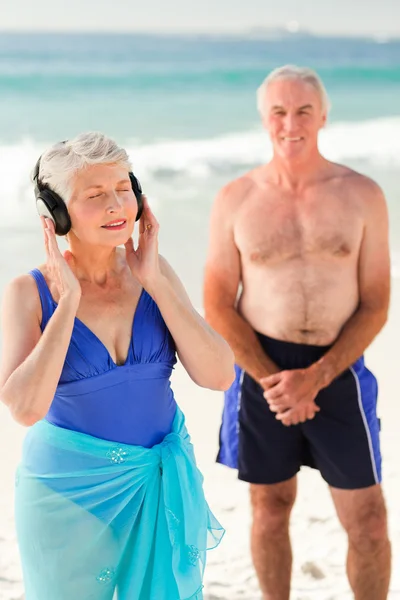 Kvinna som lyssnar på lite musik på stranden — Stockfoto