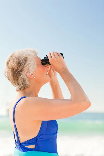 Seniorin beobachtet Vogel am Strand — Stockfoto