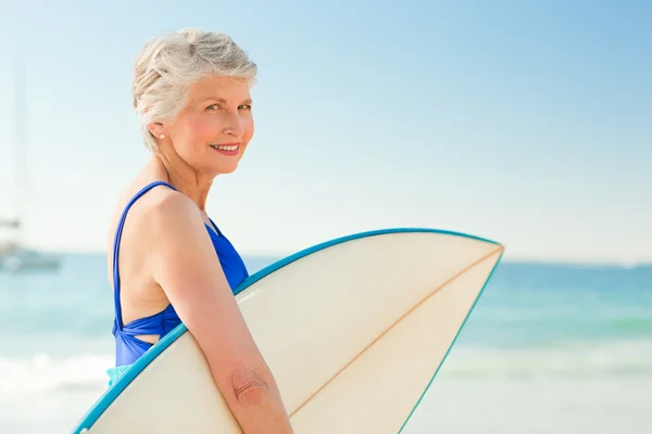 ビーチで彼女のサーフボードを持つ女性 — ストック写真