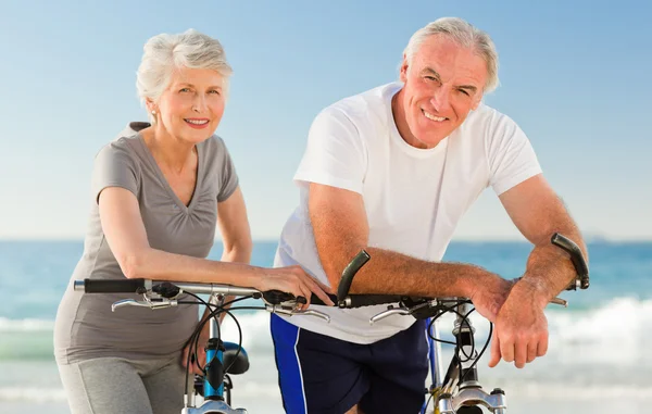 Rentnerpaar mit Fahrrädern am Strand — Stockfoto