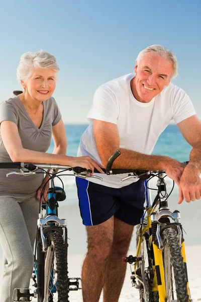 Пара пенсионеров с велосипедами на пляже — стоковое фото
