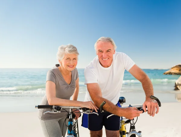Casal aposentado com suas bicicletas na praia — Fotografia de Stock