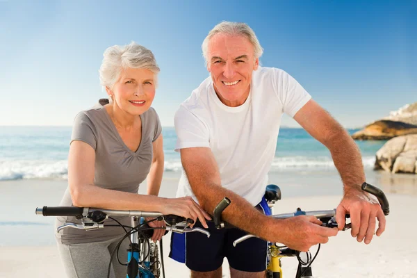 Gepensioneerde paar met hun fietsen op het strand — Stockfoto