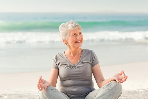 Старшая женщина практикует йогу на пляже — стоковое фото
