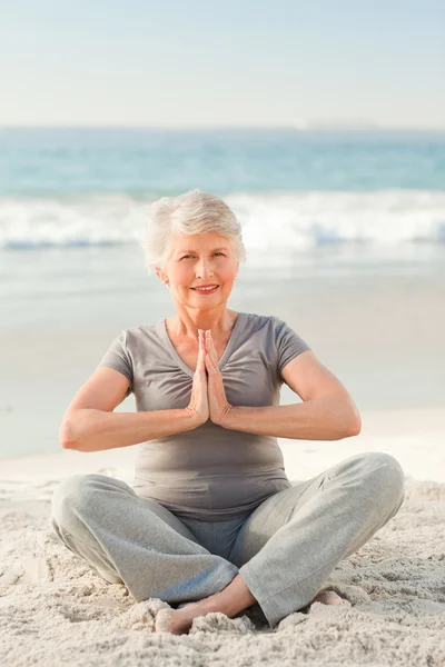 Senior woman practicing yoga on the beach — Stock Photo, Image