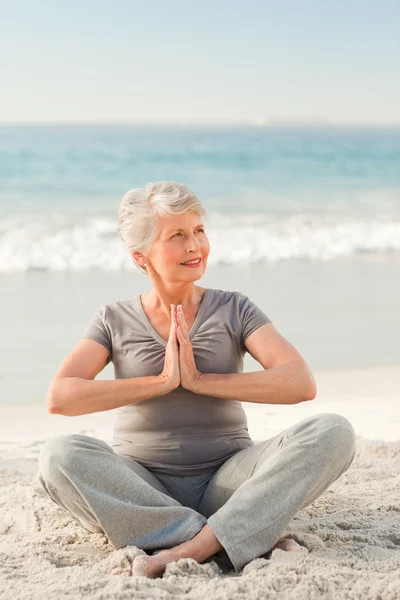 Femme âgée pratiquant le yoga sur la plage — Photo