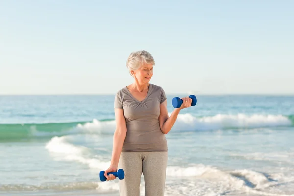 Женщина делает упражнения на пляже — стоковое фото