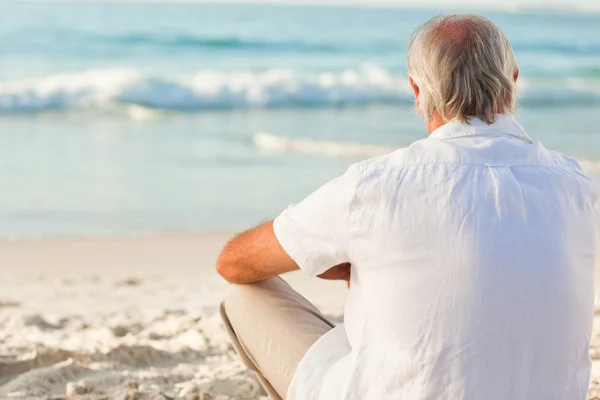 Человек, сидящий на пляже — стоковое фото