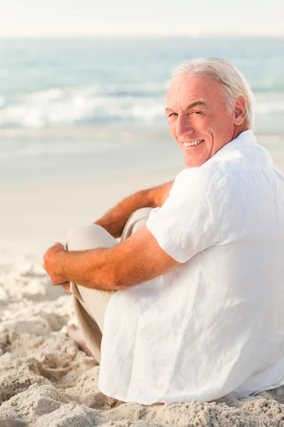 Человек, сидящий на пляже — стоковое фото