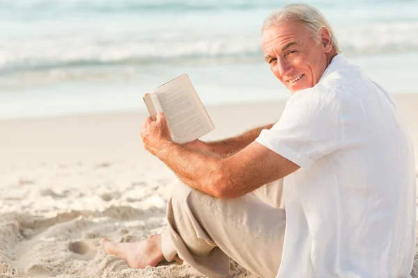 Muž s knihou na pláži — Stock fotografie