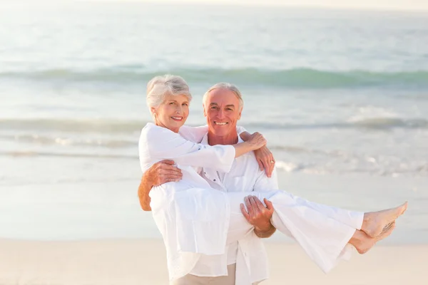 Mann trägt seine Frau am Strand — Stockfoto
