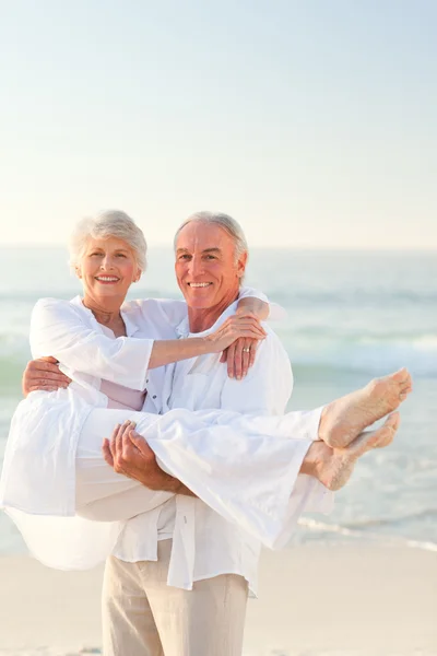 Man carrying his wife on the beach — Stock Photo, Image